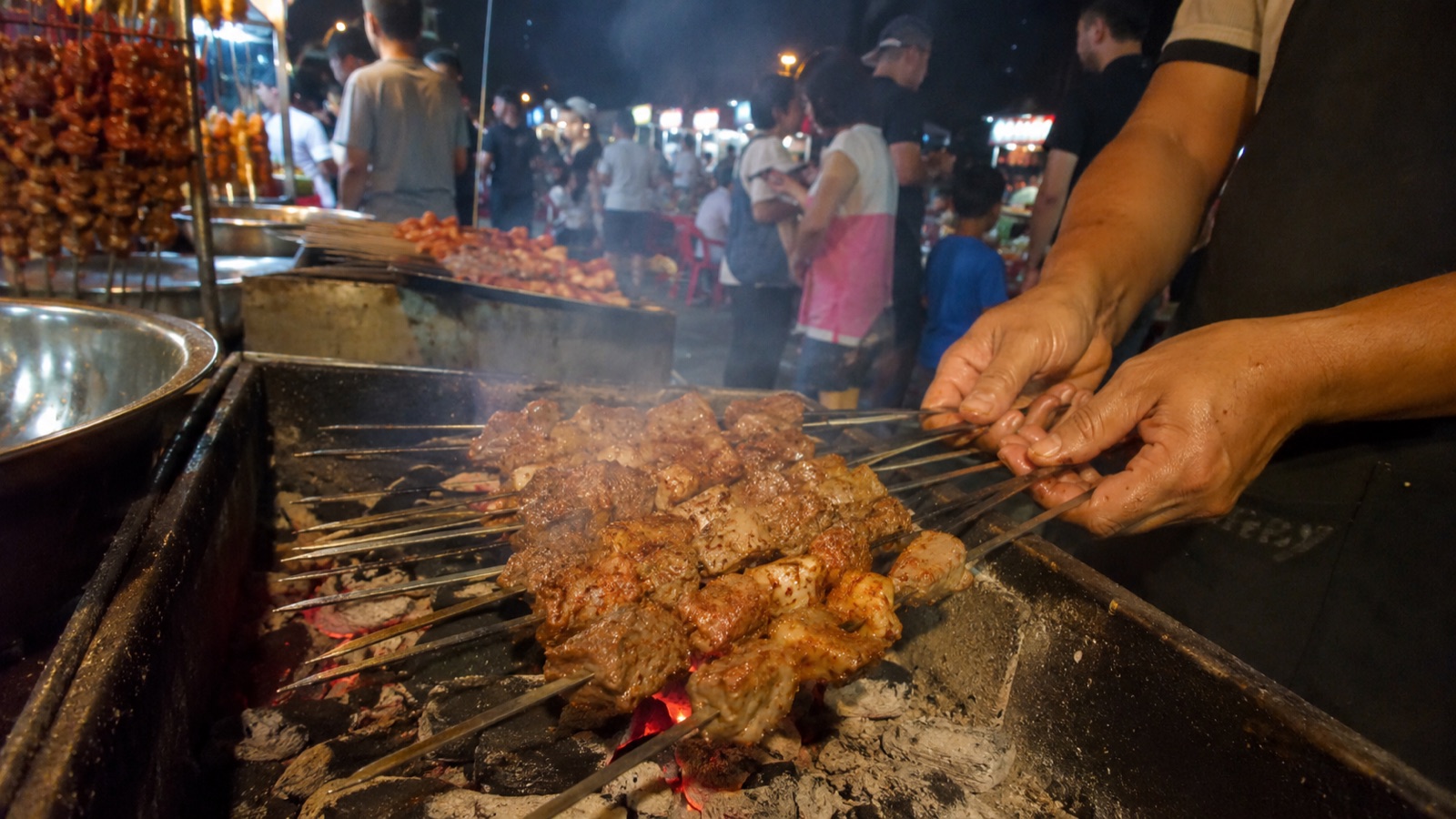 新疆夜市摊主在炭火上烤羊肉串
